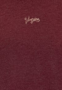 Burgundská pletená tričká s jemnou textúrou a malou vyšitou logom v svetlejšom odtieni. Priliehavý strih, hladký povrch, minimalistický štýl.
