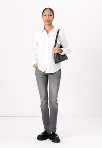 White button-up shirt, gray slim jeans, black platform shoes, and a black crossbody bag. Smooth fabric, casual fit, minimalist design.