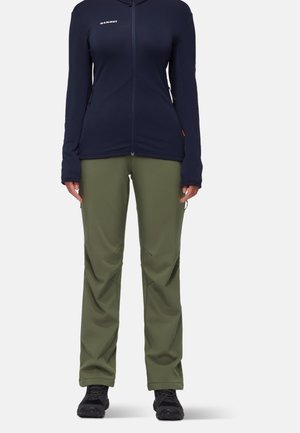 Marineblaue Fleecejacke mit Reißverschluss und langen Ärmeln, kombiniert mit olivgrünen, schmal geschnittenen Hosen und schwarzen Wanderschuhen. Strukturierter Stoff, funktionales Design.