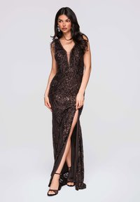 Robe de soirée noire avec un décolleté plongeant en V et des accents en plumes. Tissu orné de perles et de sequins délicats. Fente latérale dévoilant la jambe.