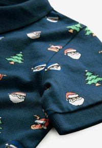 Dunkelblauer kurzärmeliger Stoff mit sich wiederholenden Weihnachtsmustern von Santa-Gesichtern, grünen Weihnachtsbäumen und Rentieren mit roten Hüten.