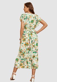 Vestido maxi floral con mangas acampanadas, cintura ajustada y falda de volantes en tonos blancos, verdes y naranjas, con un lazo en la parte posterior.