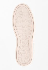 Suola di scarpa in gomma rosa con lettering in rilievo "GUESS", struttura liscia, bordi arrotondati e un sottile bordo rialzato.