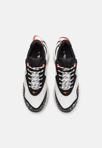 Zapatillas deportivas en blanco y negro con un acabado texturizado, que presentan acentos naranjas, cordones reflectantes y una suela con patrón. Talla 37.