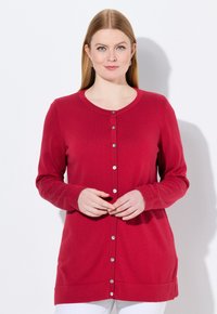 Rote Strickjacke mit langen Ärmeln, Rundhalsausschnitt und silbernen Knöpfen vorne. Glatte Textur, am unteren Rand und an den Seiten gesäumt.