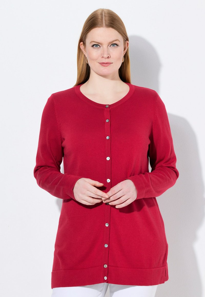 Rote Strickjacke mit langen Ärmeln, Rundhalsausschnitt und silbernen Knöpfen vorne. Glatte Textur, am unteren Rand und an den Seiten gesäumt.