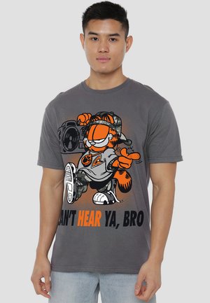Graues Baumwoll-T-Shirt mit einem orangen Cartoon-Katzenmotiv, das eine Kamera hält, Tarnakzenten und dem Text "KANN DICH NICHT HÖREN, KUMPEL" in fetter Schrift.