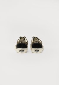 Leopard print sneakers with black suede accents, cream sole, and logo on the heel. Slip-on style with cushioned interior.