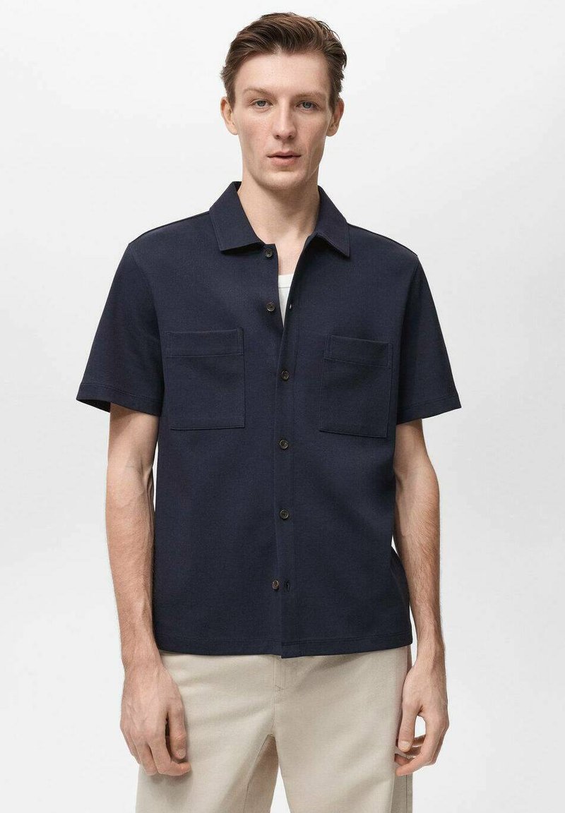 Marineblauwe korte mouwen shirt van lichtgewicht stof met twee borstzakken en een knoopsluiting aan de voorkant. Eenvoudig kraagontwerp met een rechte pasvorm.