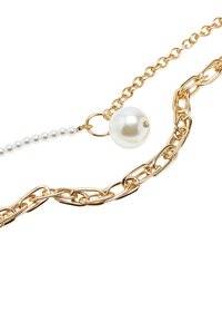 Złoty naszyjnik z łańcuchem, zwracający uwagę na dużą perłę oraz małe akcenty z perłami, z ogniwami o różnych rozmiarach i gładkim, wypolerowanym wykończeniem.