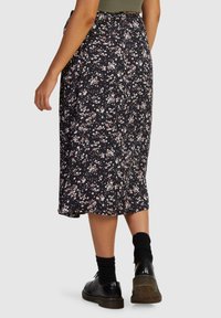 Black floral skirt featuring a flowy design, knee-length cut, small multicolored flowers, and a lightweight fabric with a smooth texture.