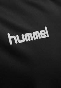 Black sports fabric featuring a large, white "hummel" logo. The texture is smooth with a slight sheen, displaying a clean design without patterns.
