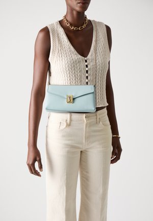 Sac à main en cuir bleu clair avec un rabat et des accessoires en or. Accompagné d'un pull en maille blanche texturée et d'un pantalon large couleur crème.