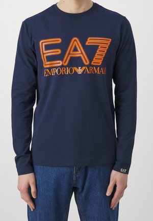 Marineblå langærmet t-shirt lavet af blød bomuld, med en markant orange logo "EA7 EMPORIO ARMANI" på fronten. Indeholder et lille mærke med brandnavnet ved kanten.