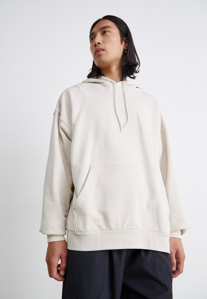 Haut de hoodie surdimensionné beige clair en tissu doux. Comprend une poche kangourou, une capuche avec cordon de serrage ajustable et des poignets côtelés.