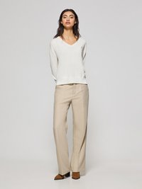 Ljus krämfärgad V-ringad tröja med ribbade muddar, tillsammans med beige vida byxor. Bruna ankelboots med klackar fulländar outfiten. Minimalistisk design.