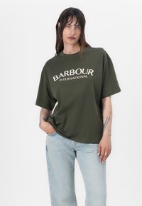 Õliva roheline ülisuur t-särk, millel on valge kiri "BARBOUR INTERNATIONAL". Valmistatud puuvillast, lühikeste varrukatega ja lõdva istuvusega.