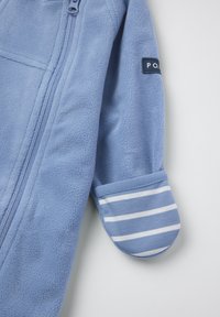 Lichtblauwe fleece jacket met een ritssluiting aan de voorkant, met gestreepte lichtblauwe en witte manchetten en een rechthoekige patch op de mouw.