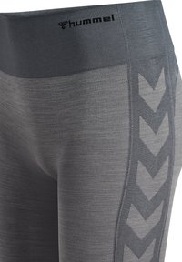 Graue Leggings mit strukturiertem Finish, ausgestattet mit einem breiten Bündchen und einem Zickzackmuster an der Seite, mit "hummel" am oberen Rand.