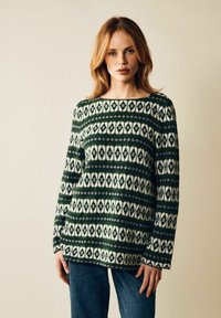 Grön och krämfärgad mönstrad tröja med en lös passform, som har geometriska mönster och en bred halsringning. Texturerad stickad tyg.