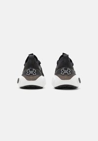 Black athletic shoes with a textured upper, featuring a white sole and branding on the heel, designed for comfort and performance.