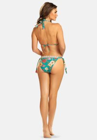 Turkusowy bikini w kwiaty z wiązanym na plecach topem halter i dołem z wiązaniami po bokach. Posiada koronkowe wykończenia oraz wyraziste kwiaty na jednolitym tle.