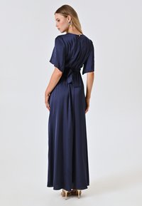 Navy Satin-Maxikleid mit kurzen Ärmeln, einer gebundenen Taillendetail und einem Schlüsselrücken. Das Kleid hat eine glatte, fließende Textur.