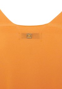 Tessuto lavorato a maglia arancione con una superficie liscia, caratterizzato da un'etichetta quadrata dorata sul retro con il nome del marchio inciso e due fori.