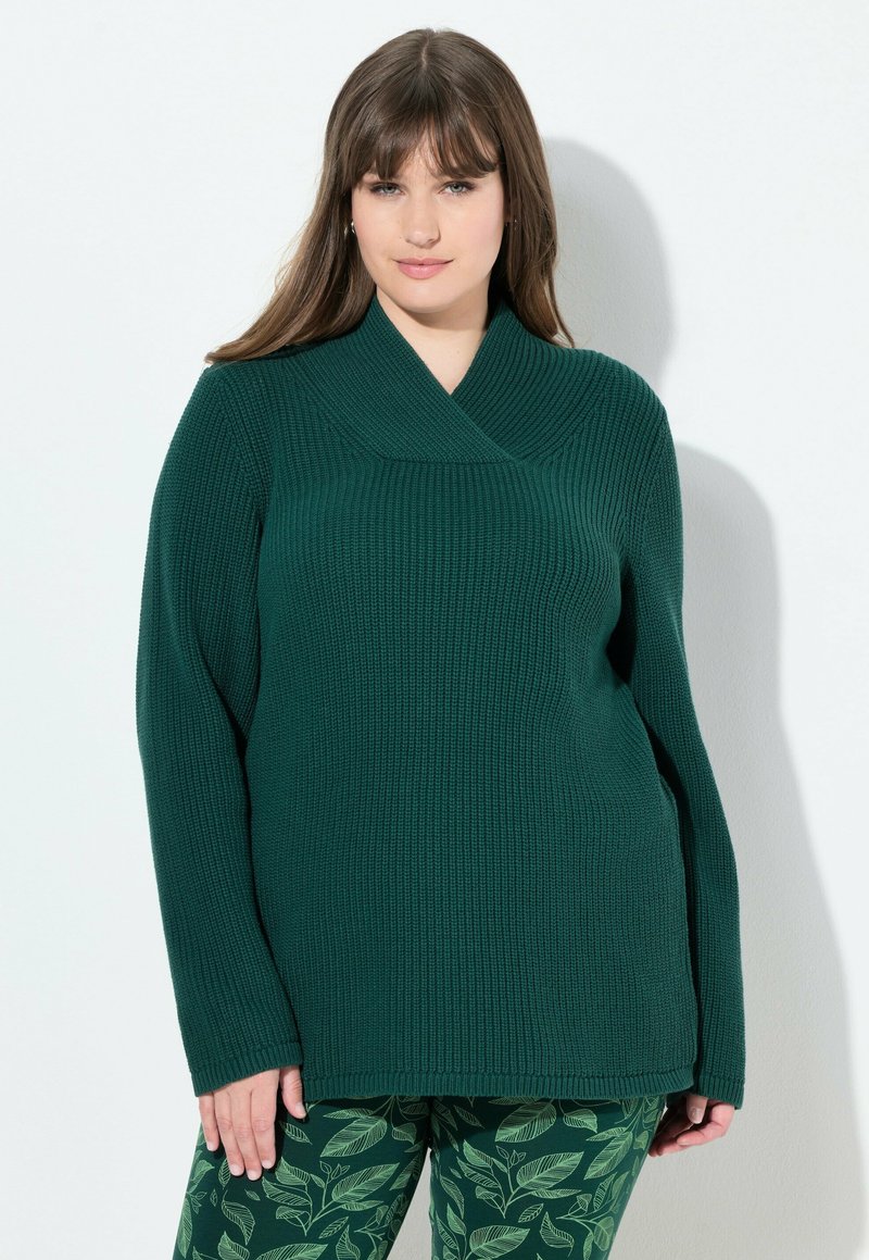 Mörkgrön stickad tröja med bred krage, långa ärmar och avslappnad passform, ihopparad med leggings med mönster av lövdesign.
