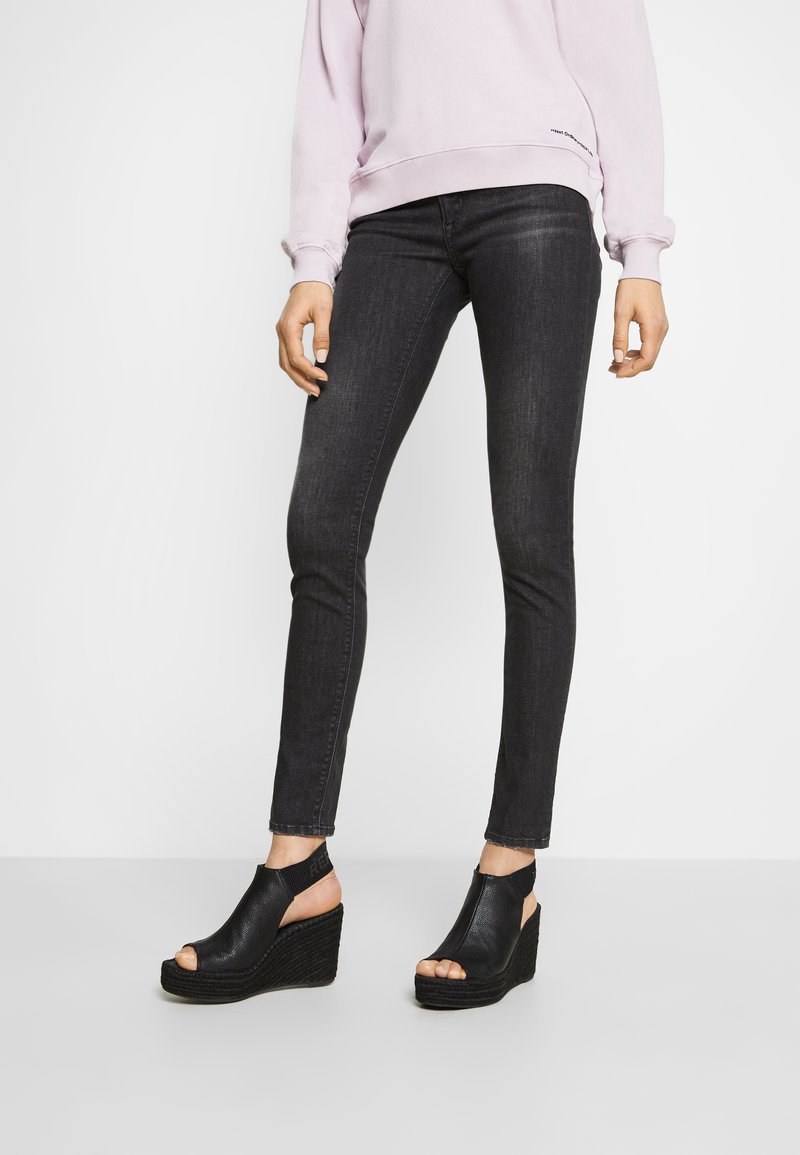Sandalias de cuña negras con diseño de punta descubierta y laterales cortados, con material de cuero texturizado y una suela intermedia de yute trenzado.