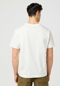 Hvid bomulds T-shirt med korte ærmer og rund halsudskæring, med et ensfarvet design og en afslappet pasform. Bagview vist.