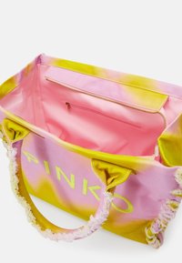Vaaleanpunainen ja keltainen kravattivärjätty kassi, jossa on risat kahvat, "PINKO" -logo ja avoin yläosa, joka paljastaa vaaleanpunaisen vetoketjullisen sisätaskun.