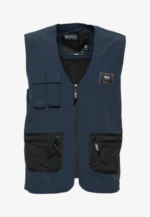 Tumesinine vest, millel on võrgusilmaga taskud ja tõmblukkudega sulgurid. Omab esimest tõmblukku, kahte rinna taskut ja kangast märgistust. Kerge materjal.