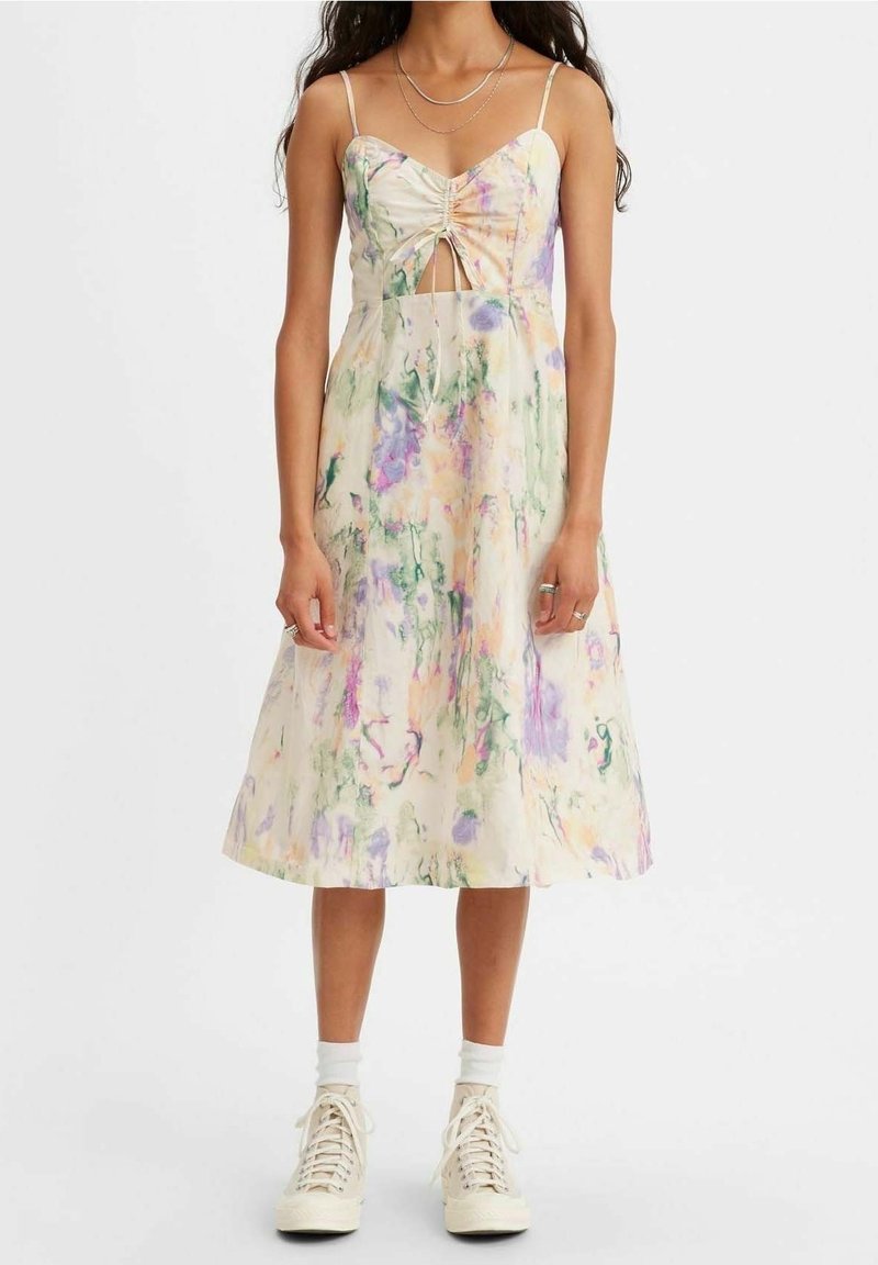 Robe midi à imprimé floral dans des couleurs pastel, avec un détail noué à l'avant, des bretelles spaghetti et une silhouette ample en ligne A. Chaussures décontractées présentées.