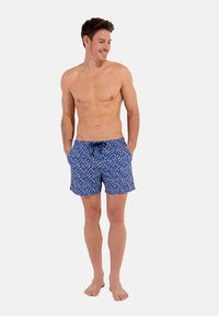 Un short de bain bleu avec un motif coloré de formes abstraites. Il dispose d'une taille élastique avec un cordon de serrage et de poches latérales.