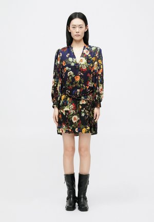 Floral wrap dress with long sleeves, featuring a navy base and vibrant multi-color flowers, accompanied by knee-high black leather boots.