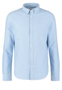 Chemise bleu clair à manches longues avec poche avant et col boutonné, présentée sur un fond blanc uni.