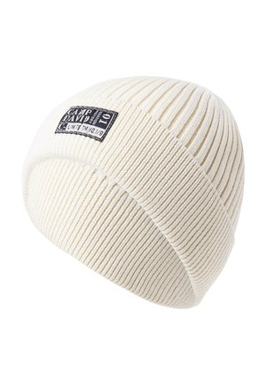 Cream-colored knit beanie with ribbed texture and a folded cuff. Features a black logo patch on the front with a white border.