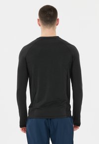 Langärmliges Sportshirt in einheitlichem Schwarz mit glatter Textur, ausgestattet mit Raglanärmeln und einem schlichten Rundhalsausschnitt.