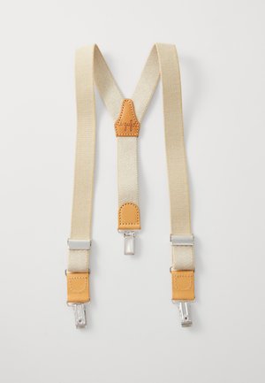 Tirantes beige con acentos de cuero y clips plateados. Diseño ajustable con un parche central de cuero que presenta detalles de costura.