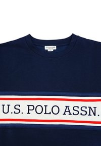 Námořnická modrá tričko vyrobené z bavlny s kulatým výstřihem a horizontálním bílým pruhem, který má červené a modré pruhy a logo "U.S. POLO ASSN.".