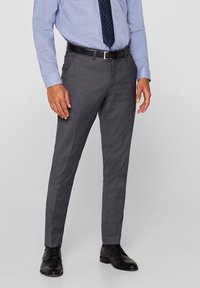 Pantaloni grigi su misura con una texture liscia, vestibilità slim e vita media, completi di tasche laterali. Indossati con una camicia azzurro chiaro e una cravatta a pois.