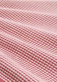 Textilstoff in Pink und Weiß, mit einem karierten Muster und einer strukturierten Oberfläche, die ein gewebtes, geometrisches Design zeigt.