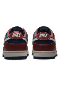 Un paio di sneaker Nike rosse, blu navy e bianche viste dal retro, con loghi Nike ricamati sulle linguette del tallone e suole testurizzate.