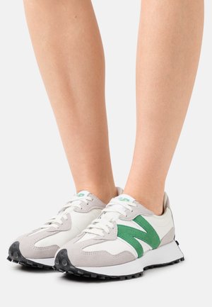 Valkoiset ja vaaleanharmaat urheilukengät, joissa vihreät yksityiskohdat, teksturoitu mokkainen muotoilu ja kontrastivärinen musta kumipohja.