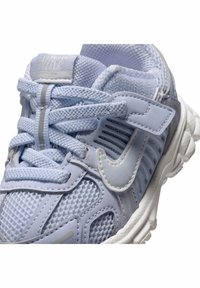 Jasnoniebieski sportowy but z siateczkowego i syntetycznego materiału, z widocznym logo Nike, solidnymi sznurowadłami i teksturowaną podeszwą.