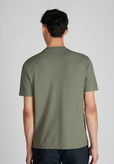 Camiseta de manga corta en color verde oliva, hecha de algodón suave, con cuello redondo y un ajuste relajado, con sutiles detalles de costura en el dobladillo.