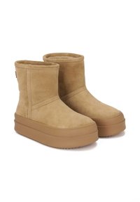 Botine din suede bej cu vârf rotund și talpă din cauciuc groasă de 3 cm. Prezintă cusături vizibile și o textură netedă. Fără embellishments.