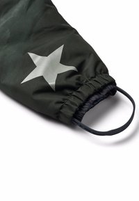 Manche en tissu vert avec une ouverture froncée, ornée d'un grand motif en étoile gris. Comprend un détail en métal circulaire noir à l'extrémité.