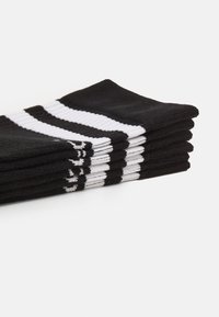 Schwarze Baumwollsocken gestapelt, mit weißen horizontalen Streifen. Die Textur ist glatt mit gerippten Akzenten am oberen Ende und zeigt ein schlichtes Design.